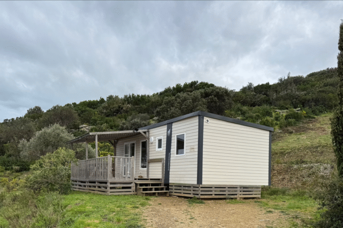 Exterior view of the Mobile Home Standard – Two Bedrooms at Camping Vista Mare, set against the hillside and surrounded by Mediterranean vegetation in Cap Corse.