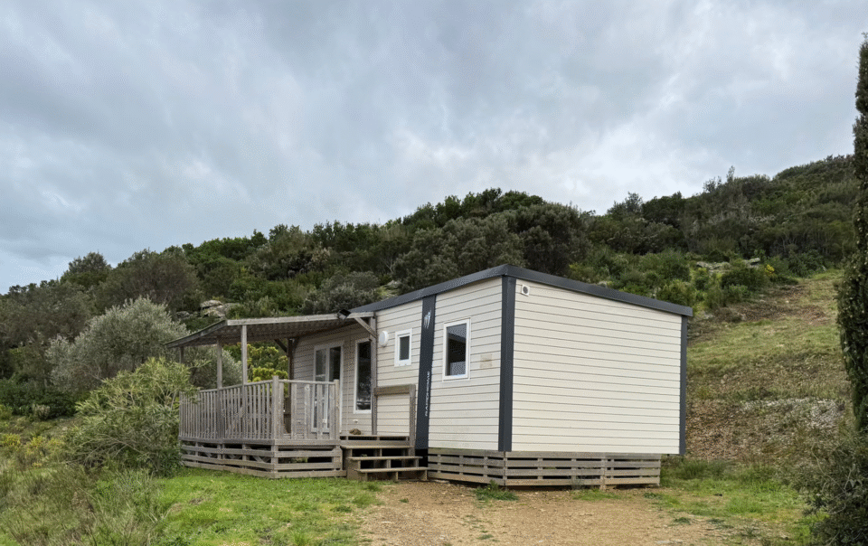 Exterior view of the Mobile Home Standard – Two Bedrooms at Camping Vista Mare, set against the hillside and surrounded by Mediterranean vegetation in Cap Corse.