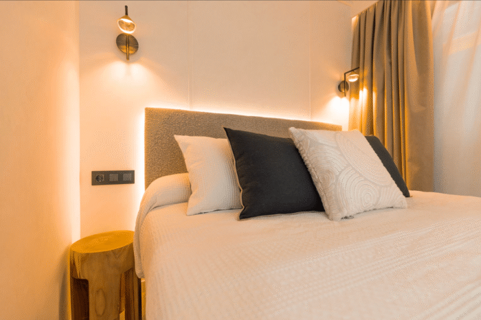 Interior view of the Luxury Bungalow at Camping Vista Mare, featuring a modern double bedroom with soft lighting, elegant wall lamps, neutral decor, and a comfortable bed.
